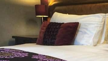 A hotel room with a bed, a nightstand, and a wall-mounted lamp.