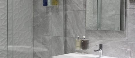 A modern bathroom with a white sink, a mirror, and marble-patterned walls.