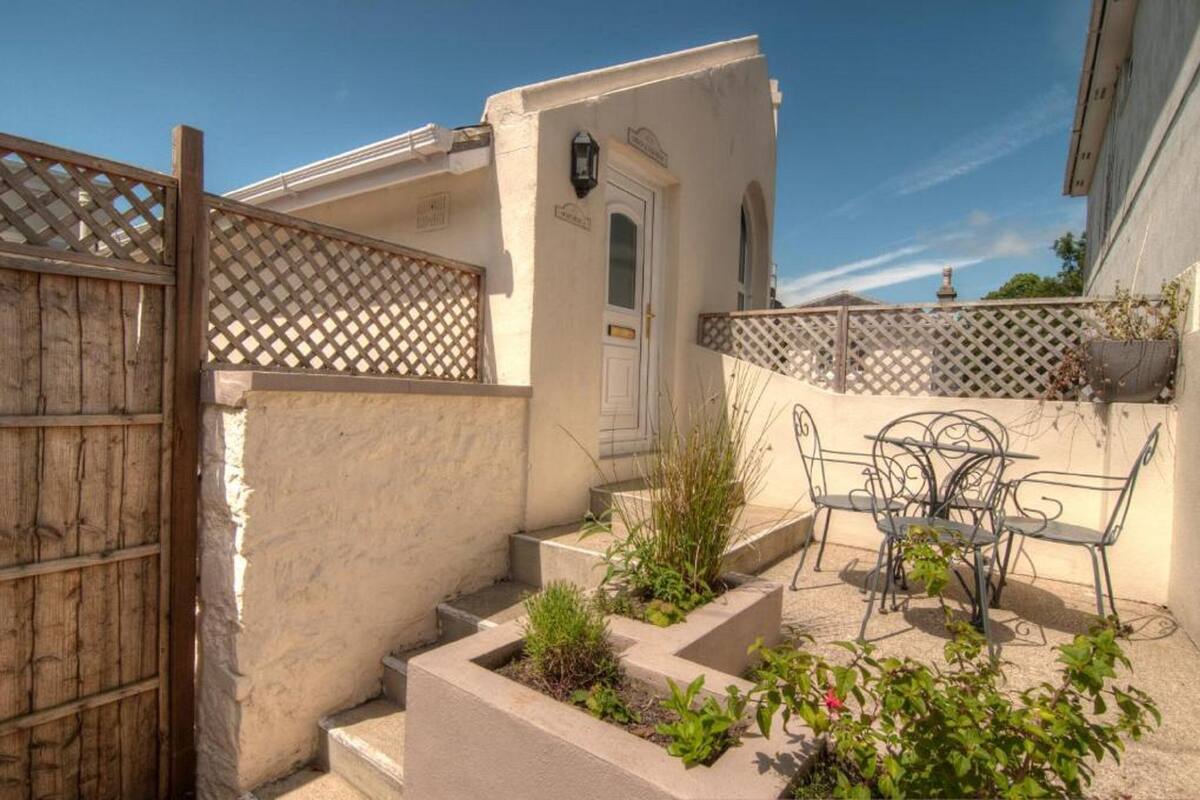 A courtyard with a wooden gate, a white door, and a metal table with chairs.