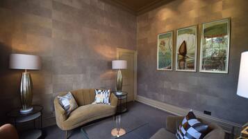 Un salon moderne avec un canapé beige, deux tables d’appoint avec des lampes et trois œuvres d’art encadrées accrochées au mur.