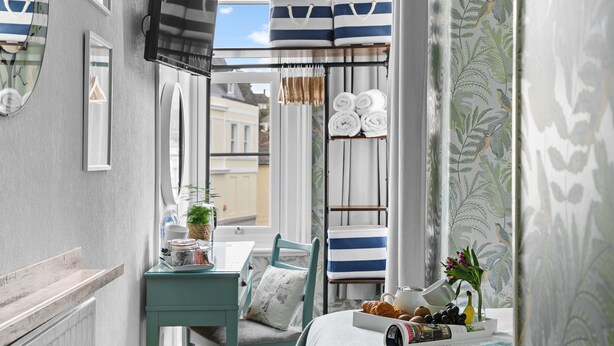 A bedroom with a bed, a bedside table with a lamp, a chair, and a window with curtains. - Sandway House (Torquay)