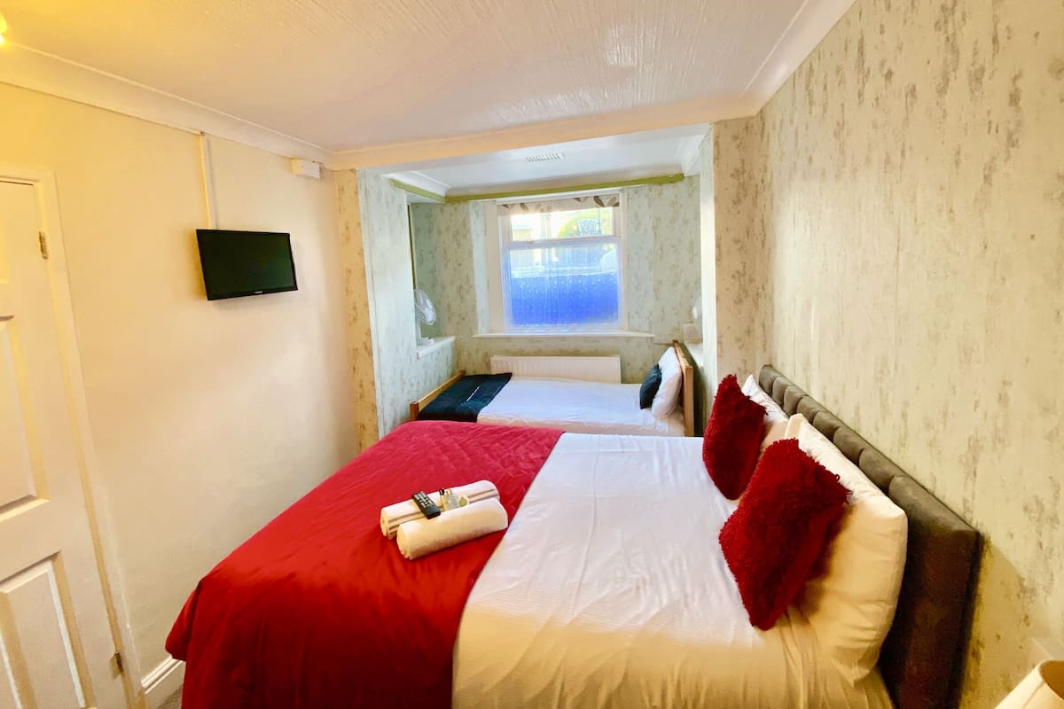 A hotel room with a bed, a television, a window, and a view of the outside.