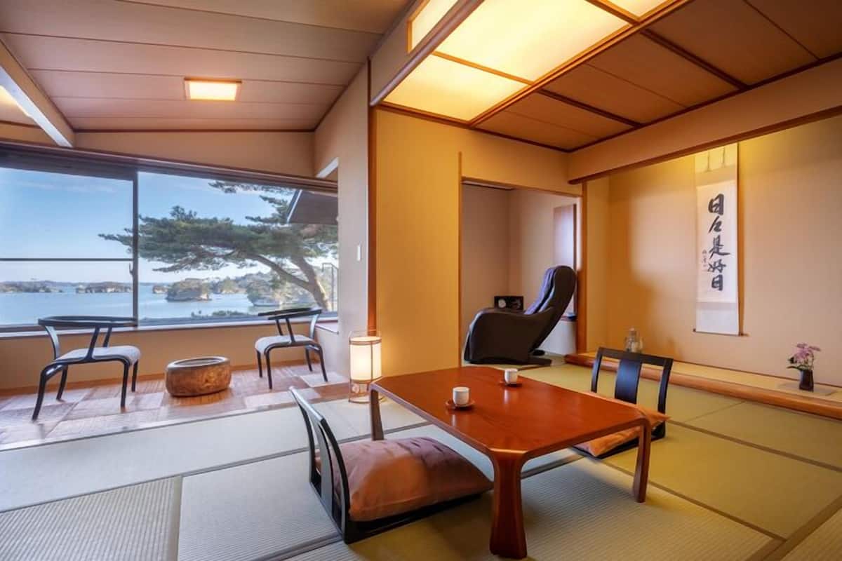 Una habitación japonesa tradicional con suelo de tatami, una mesa baja y una silla.