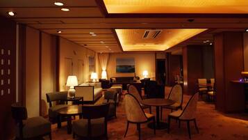 A hotel lobby with a seating area, tables, and lamps.