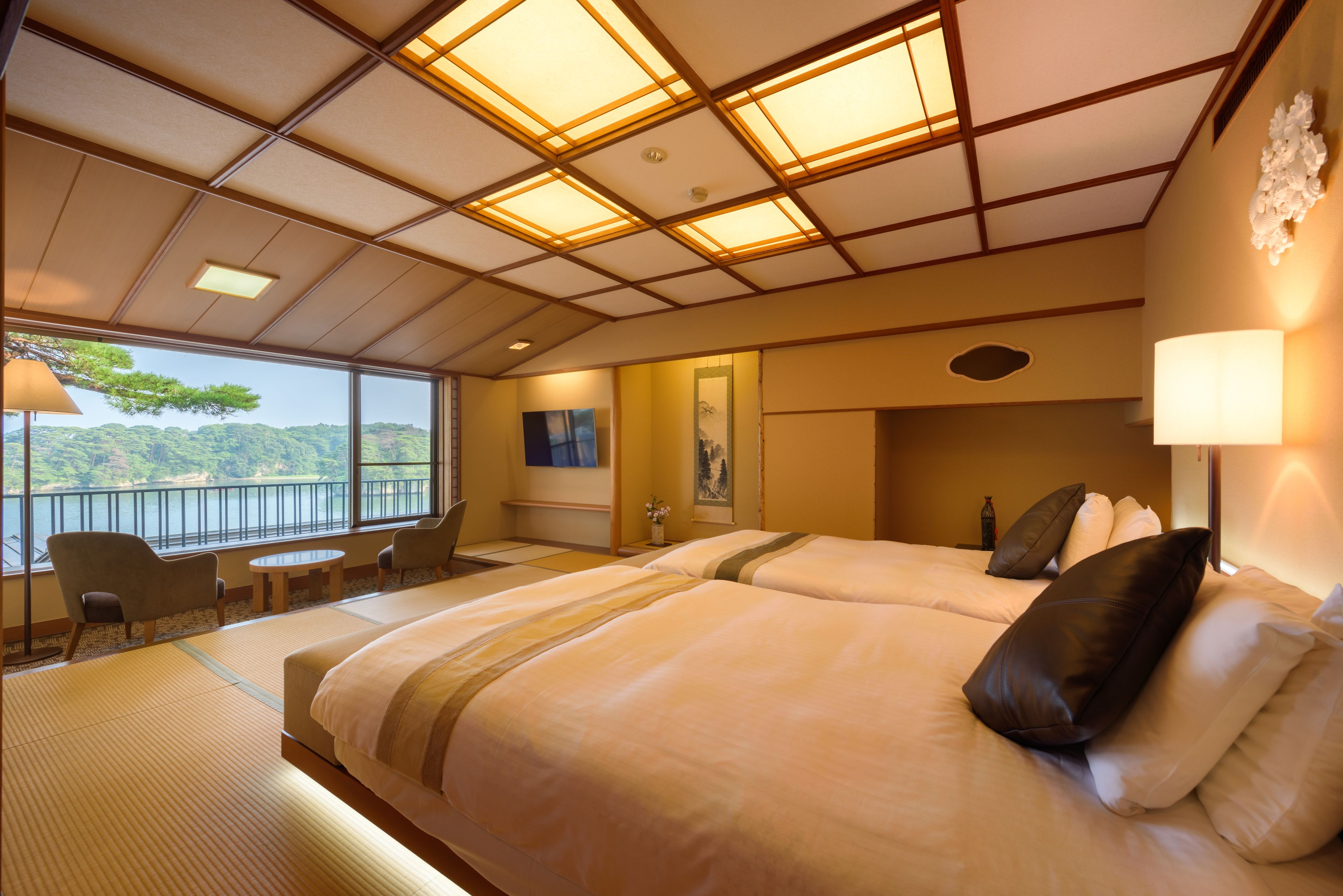 A hotel room with a large bed, two bedside tables, a chair, and a view of a balcony with a railing.