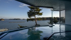 Een modern interieur met een groot raam dat uitkijkt over een wateroppervlak en een boom.