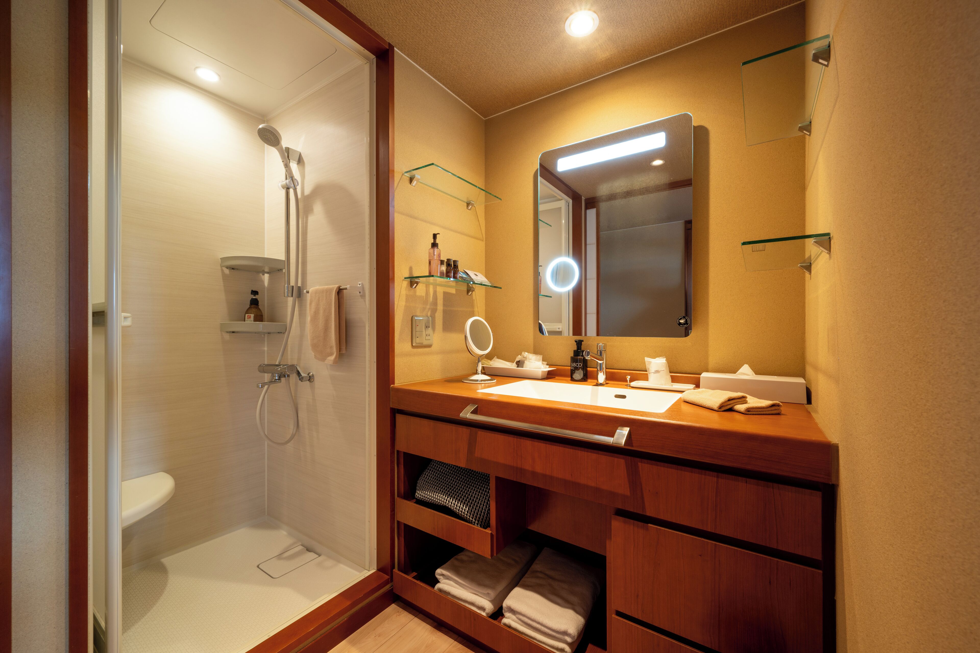 Un bagno moderno con cabina doccia in vetro, un mobile vanitario con specchio e ripiani per articoli da toilette.