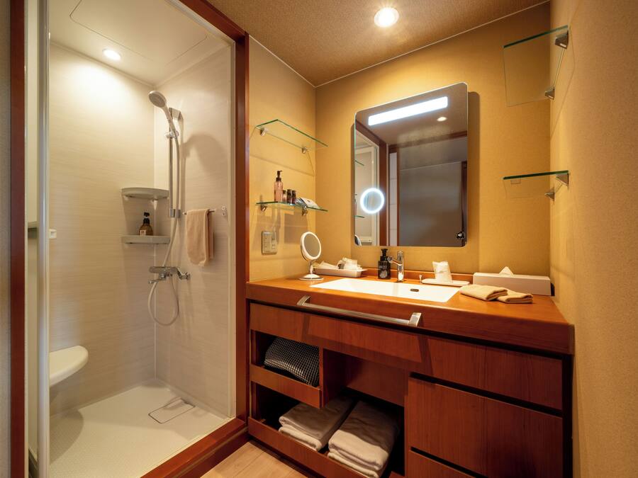 Un bagno moderno con cabina doccia in vetro, un mobile vanitario con specchio e ripiani per articoli da toilette.