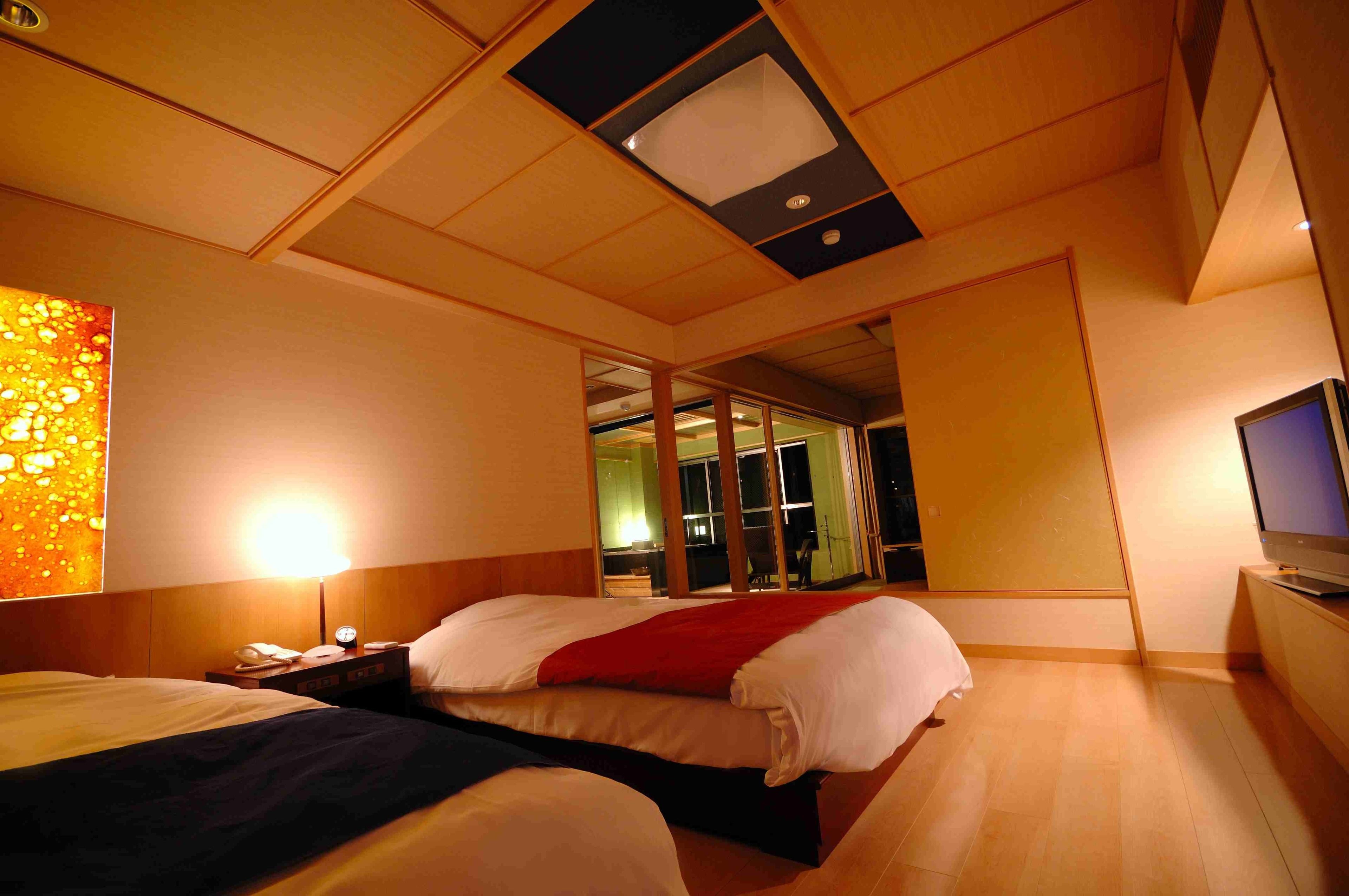 A hotel room with two beds, a TV, and a large window.