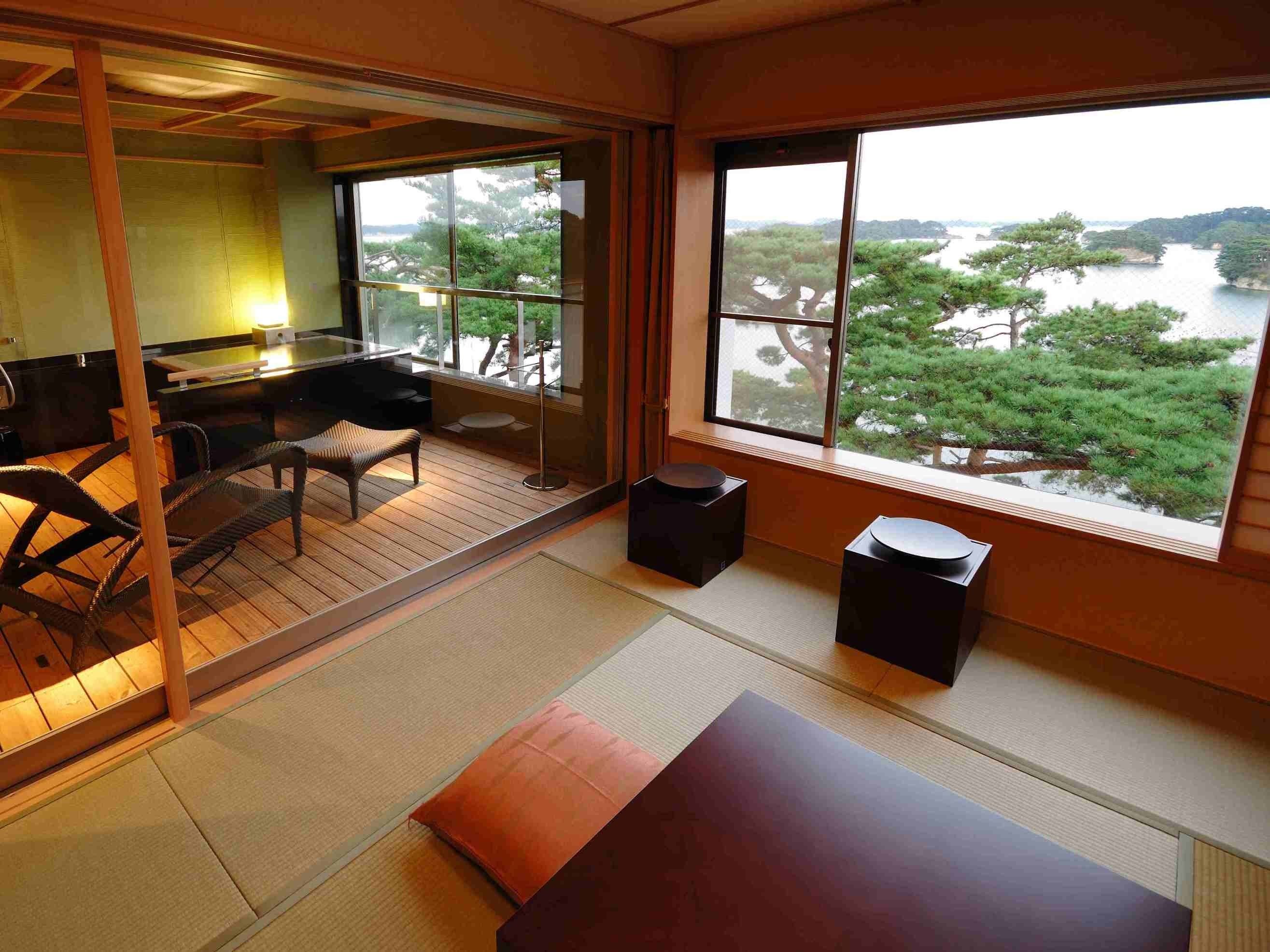 A traditional Japanese-style room with tatami flooring, a low table, and a view of a lake with trees.