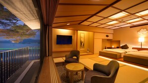 Een hotelkamer met balkon, bed, een slaapbank, een tafel en een televisie.