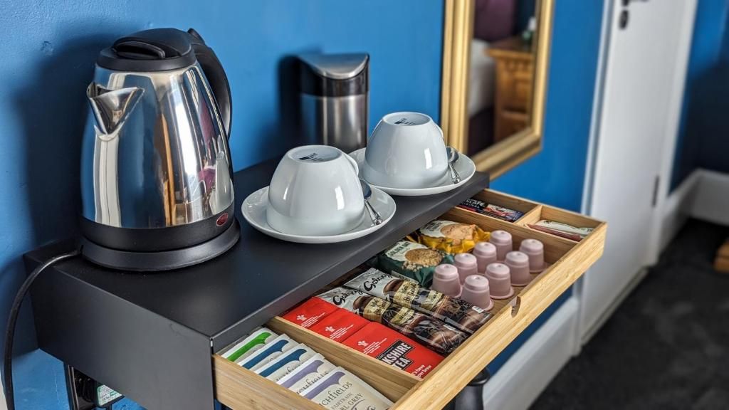 A kitchenette with a kettle, two cups, and a tray with tea and snacks.