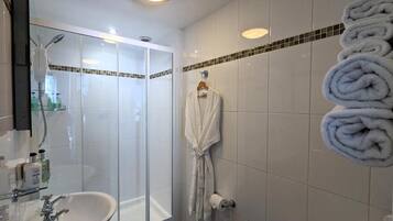 A bathroom with a glass-enclosed shower, a sink, and a towel rack with towels.