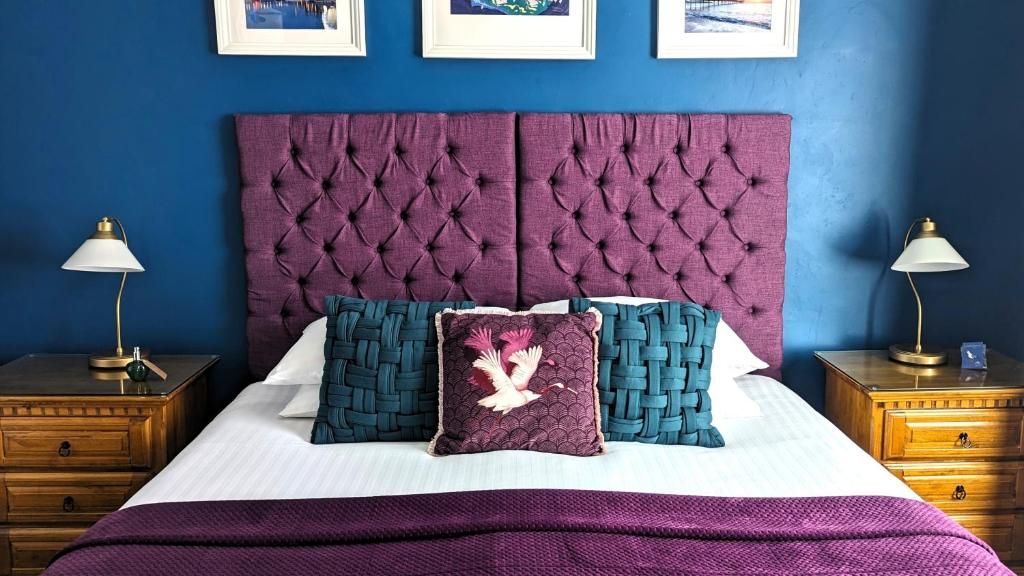 A bed with a tufted headboard, two nightstands with lamps, and a purple throw blanket.