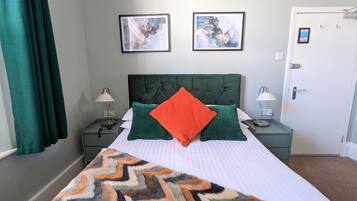 A neatly arranged hotel room with a large bed, two bedside tables with lamps, and two framed artworks on the wall.