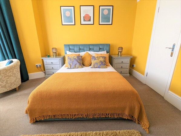 A bedroom with a bed, nightstands, a chair, and a door.