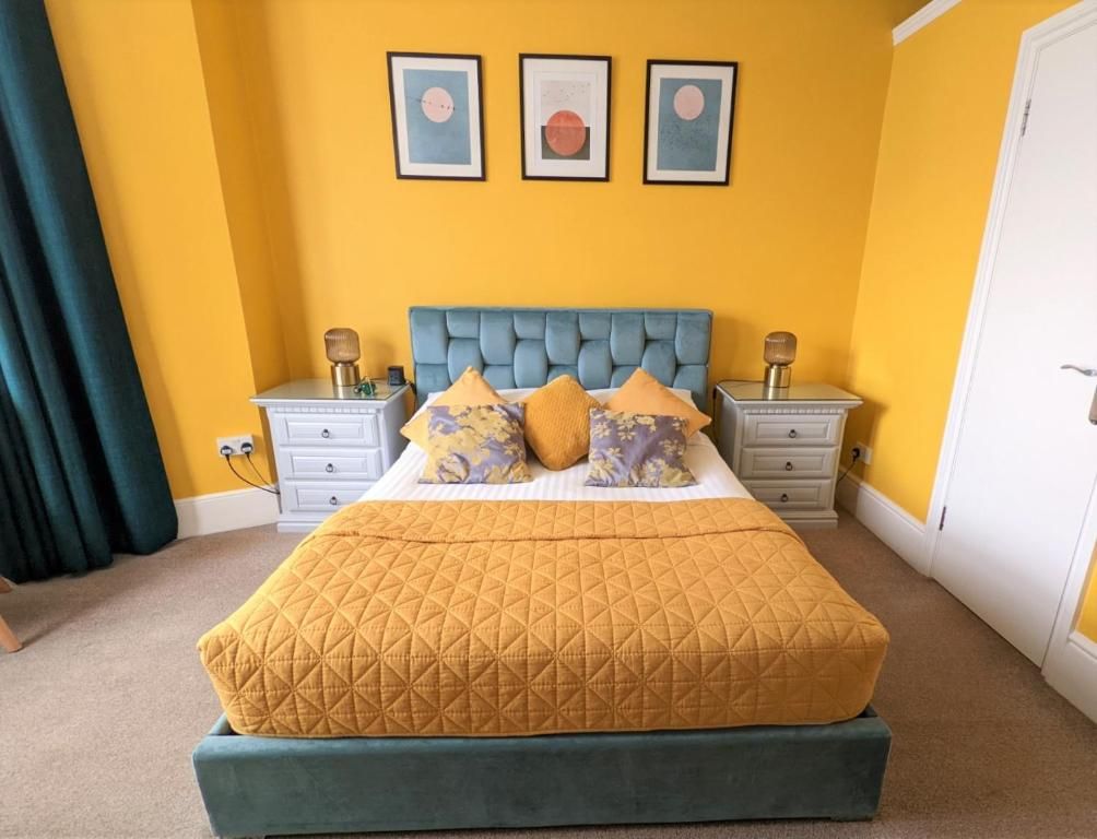 A bed with a quilted cover, two bedside tables with lamps, and a wall with three framed pictures.