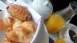 A breakfast setting with croissants, a teapot, a glass pitcher, and a cup of coffee. - Villa Marina (Torquay)