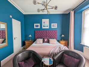 A bedroom with a large bed, two bedside tables, a chandelier, and a window with curtains. - Villa Marina (Torquay)