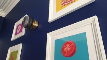A wall with framed pictures, including a tomato slice and bacon.