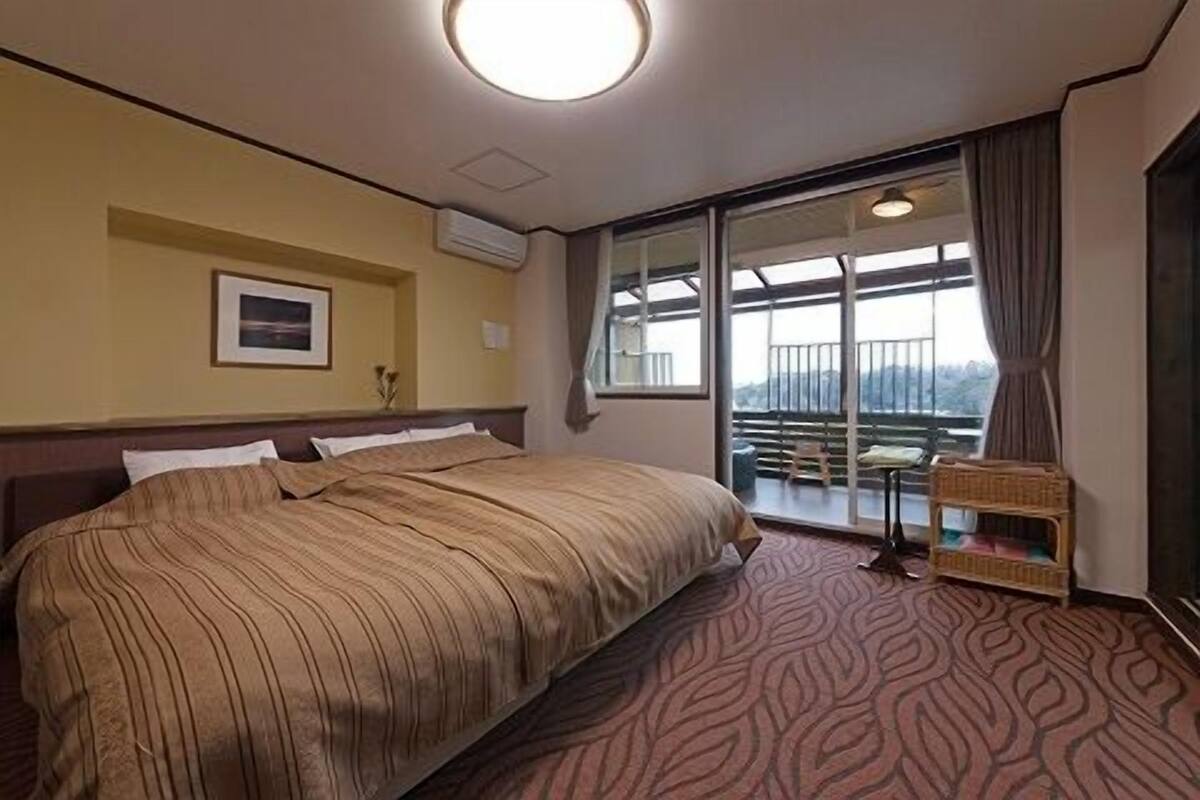 Ein Hotelzimmer mit einem großen Bett, einem Fenster mit Aussicht, einem kleinen Tisch und einem Sessel.