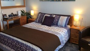 Un dormitorio ordenado con cama, mesitas de noche, escritorio y espejo.