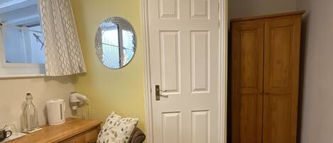 A room with a wooden desk, a chair, a white door, and a wooden wardrobe.