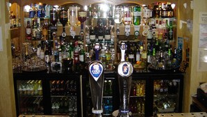 A bar area with multiple liquor bottles and two prominent beer taps labeled "Cold Premium" and "Foster's".