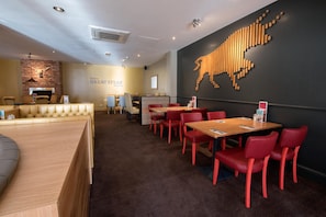 A restaurant interior with a bar area, red chairs, and a wall-mounted wooden design. - Premier Inn Walsall - M6 J10 (Walsall)