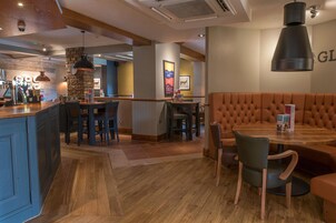 Un interior de restaurante con una zona de bar, disposición de mesas y un menú a la vista.