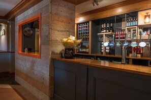A bar area with a clock, shelves of bottles, and beer taps. - Premier Inn Walsall - M6 J10 (Walsall)