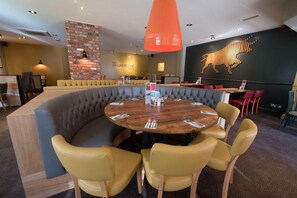 Un restaurante con una mesa redonda, asientos acolchados y una pared de ladrillo decorativa.