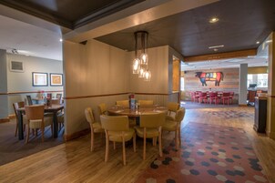 Un vestíbulo de hotel con una mesa redonda y sillas, una alfombra estampada y una pared con un letrero de indicaciones.