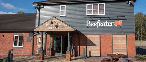 Un edificio con un letrero que dice 'Bentley Green Beeffeater' y un patio con mesas y bancos.