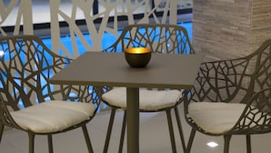 Un coin repas avec une table et deux chaises, un bol décoratif posé sur la table et un fond éclairé en bleu.