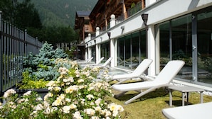 Un hôtel doté de chaises longues extérieures, d’une construction en bois et offrant une vue sur les montagnes.