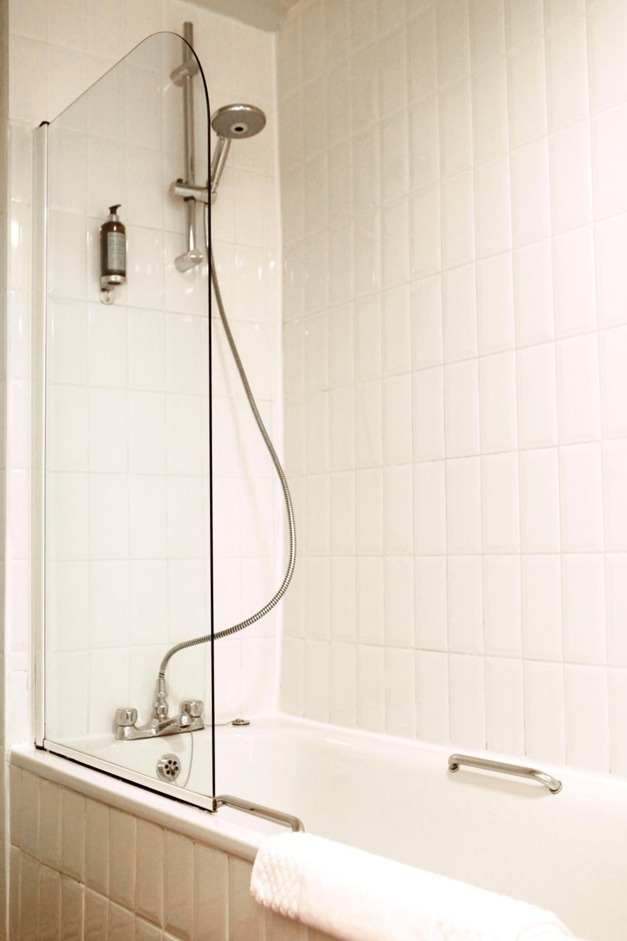 Un baño moderno con ducha envuelta en vidrio, bañera blanca y pared de azulejos.
