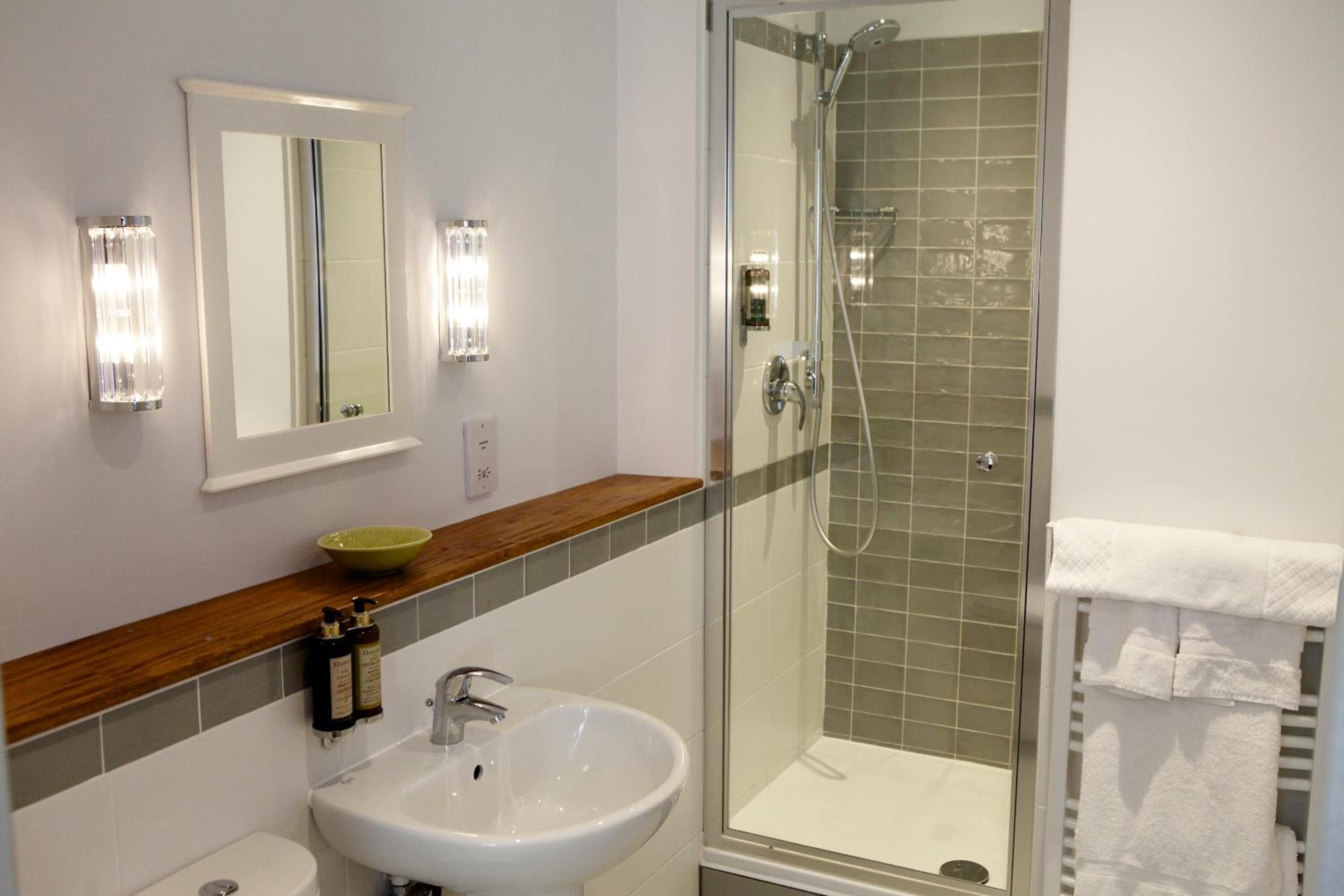 A bathroom with a sink, mirror, and shower.