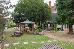 A garden with picnic tables, a gazebo, and a large tree. - Heart of England, Northampton by Marston's Inns (Northampton)