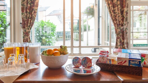 A breakfast table with a bowl of fruit, glasses of orange juice, and various breakfast items. - Heart of England, Northampton by Marston's Inns (Northampton)