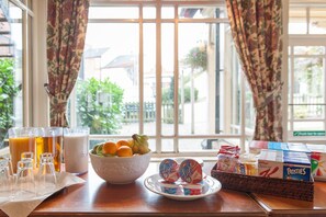 A breakfast table with a bowl of fruit, glasses of orange juice, and various breakfast items. - Heart of England, Northampton by Marston's Inns (Northampton)