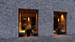 A stone facade with two large windows, each with a wooden bench inside.