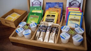 Ein Holztablett mit verschiedenen Tee- und Kaffeeprodukten, darunter Marken wie Twinings und Arriba sowie Nescafe Gold Packungen.
