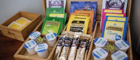 A wooden tray with various tea and coffee products, including Twinings and Arriba brands, and Nescafe Gold packets.