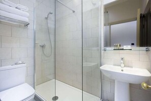 Een moderne badkamer met een douchecabine van glas, een wit wastafelmeubel en een toilet.