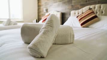 Una cama bien hecha con toallas blancas enrolladas y una almohada a rayas.