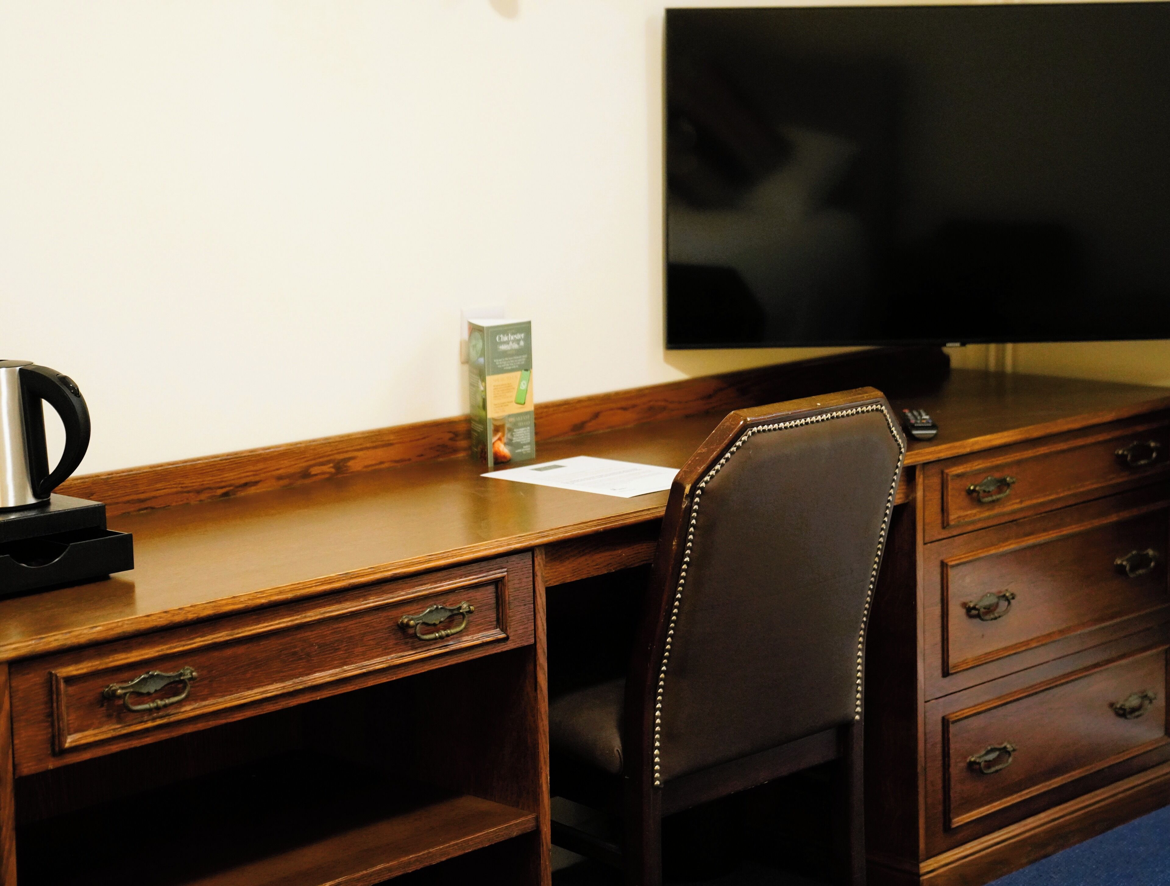 Un bureau en bois avec une chaise, un téléviseur et une boîte de lingettes désinfectantes Clorox.