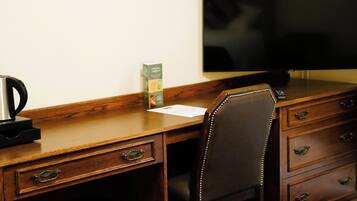 A wooden desk with a chair, a television, and a box of Clorox wipes.