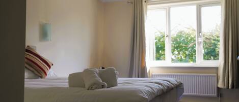 Una habitación de hotel con cama, ventana con cortinas y un radiador.