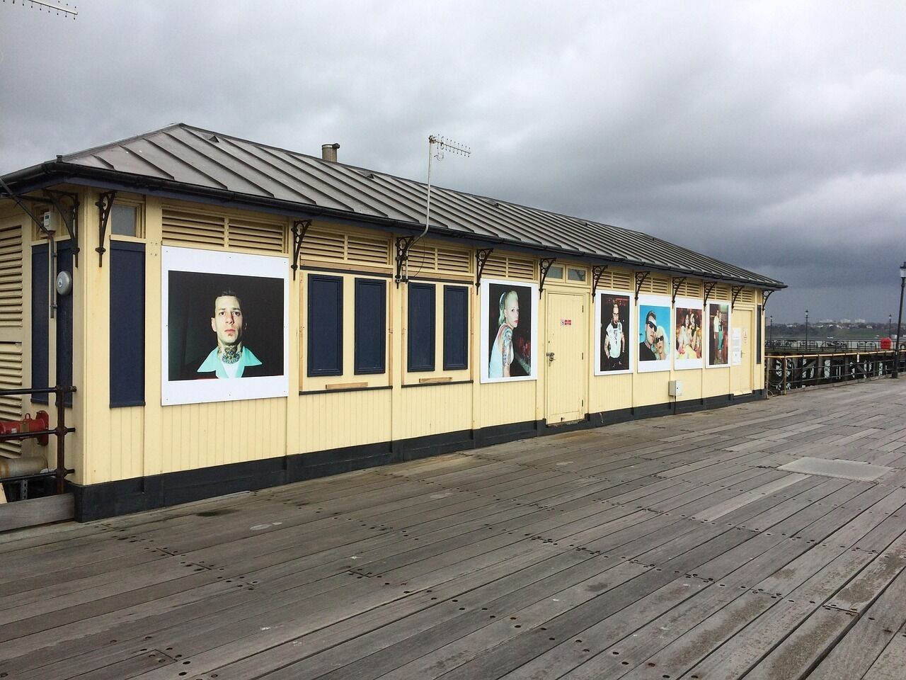 A coastal building with multiple windows, some with posters, and a wooden deck in front.